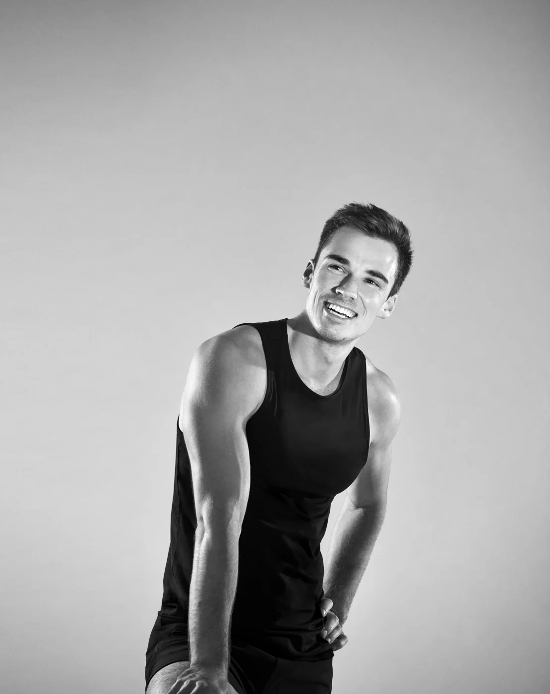 Black-and-white portrait of Sam Leicht smiling in a black sleeveless shirt