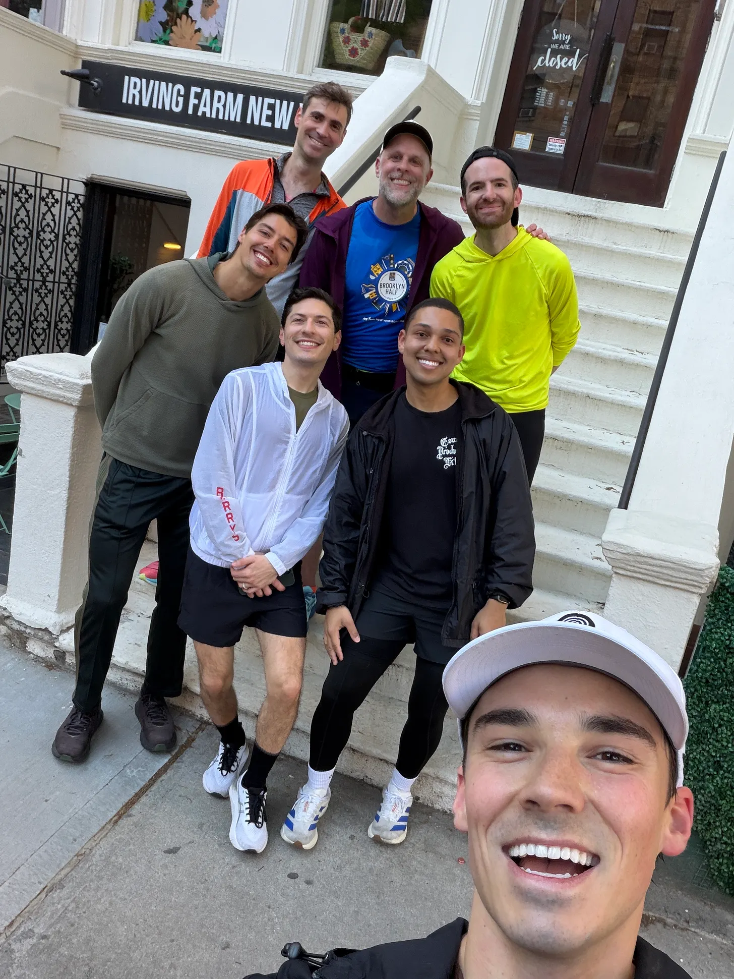 Sam Leicht smiling in a group selfie with six others outside a coffee shop